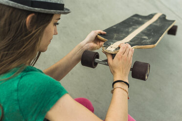 Young woman checking her skateboard - UUF004614