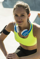 Porträt einer sportlichen jungen Frau mit blauen Kopfhörern - UUF004646