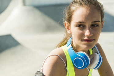 Porträt einer sportlichen jungen Frau mit blauen Kopfhörern - UUF004647