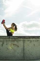 Young woman doing stretching exercises on a wall - UUF004651