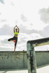 Junge Frau übt Yoga an einer Wand - UUF004662