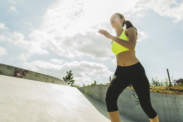 Junge Frau joggt in einem Skatepark - UUF004655