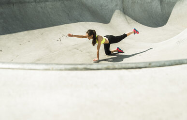 Junge Frau bei Dehnungsübungen in einem Skatepark - UUF004663