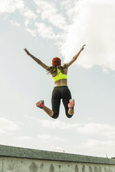 Back view of young woman jumping in the air - UUF004660