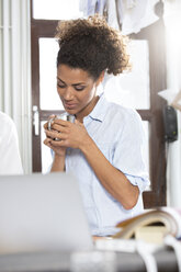 Junge Frau in der Werkstatt eines Herstellers hält eine Kaffeetasse - FKF001195