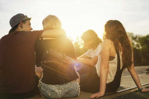 Freunde sitzen bei Sonnenuntergang im Freien zusammen - GCF000118