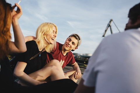Happy friends sitting together outdoors stock photo