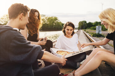 Friends sitting together outdoors sharing a pizza - GCF000097