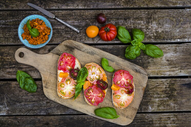 Tomatenbrot mit Heirloom-Tomaten und Basilikum auf einem Holztisch - SARF001839