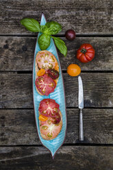 Tomatenbrot mit Heirloom-Tomaten und Basilikum auf einem Holztisch - SARF001844