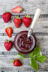 Strawberry jam in glass, strawberries on wood - SARF001853