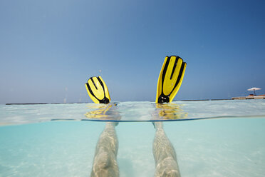 Malediven, Männerfüße mit Schwimmflossen im seichten Wasser - STKF001289