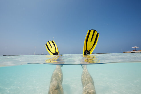 Maldives, man's feet with flippers in shallow water - STKF001289