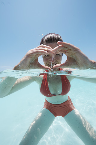 Maldives, woman shaping a heart with her hands in shallow water stock photo