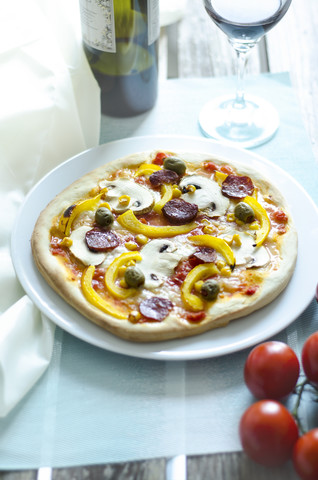 Hausgemachte Pizza mit Champignons, gelber Paprika, Tomaten, grünen Oliven, Chorizo und Rotwein, lizenzfreies Stockfoto