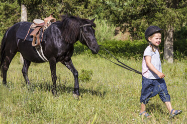 Griechenland, Korfu, Agios Georgios, kleines Mädchen führt Pferd auf einer Wiese - JFEF000687