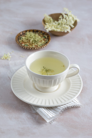 Tasse mit Holunderblütentee und Schalen mit frischen und getrockneten Holunderblüten, lizenzfreies Stockfoto