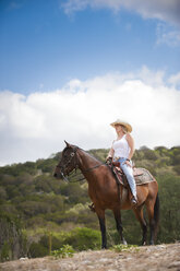 USA, Texas Hill Country, Cowgirl auf Pferd sitzend - ABAF001815