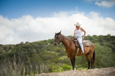 USA, Texas Hill Country, Cowgirl auf Pferd sitzend - ABAF001816