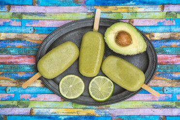 Metal tray of avocado ice lollies, avocado and slices of lime - SARF001863