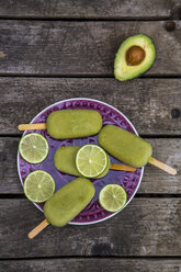 Avocado ice lollies and slices of lime on plate - SARF001869