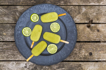 Plate of avocado ice lollies and slices of lime - SARF001870