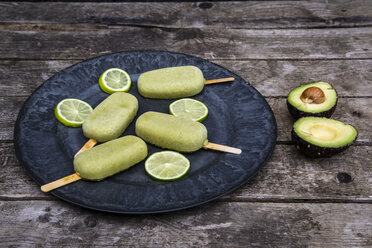 Plate of avocado ice lollies and slices of lime - SARF001872