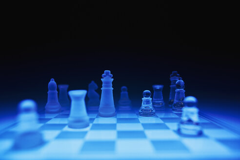 Chess pieces on blue glass board against dark background - DSCF000194