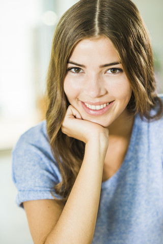 Portrait of a smiling brunette young woman with hand on chin stock photo