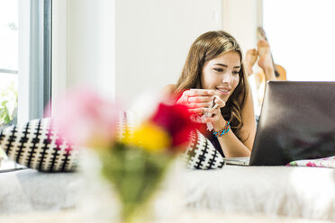 Relaxed young woman lying in bed using laptop - UUF004675