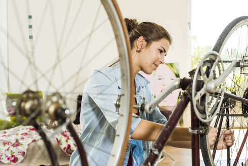 Junge Frau, die zu Hause ihr Fahrrad repariert - UUF004691