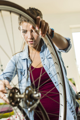 Young woman at home repairing her bicycle stock photo