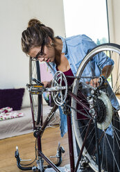 Young woman at home repairing her bicycle - UUF004697