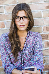Porträt einer brünetten jungen Frau mit Brille im Freien - UUF004720