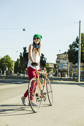 Lächelnde junge Frau mit Fahrrad auf dem Bürgersteig - UUF004728