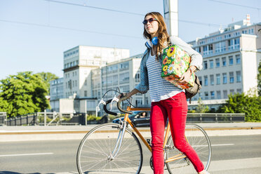 Junge Frau mit Fahrrad auf dem Bürgersteig mit Geschenkbox - UUF004734