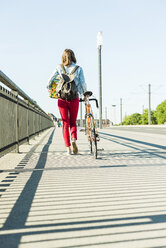 Junge Frau mit Fahrrad auf dem Bürgersteig mit Geschenkbox - UUF004737