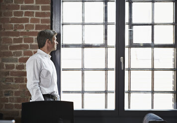 Businessman in office looking out of window - PDF000998