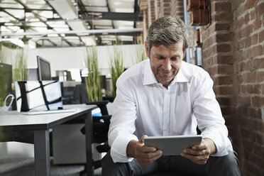 Businessman in office looking at digital tablet - PDF001008