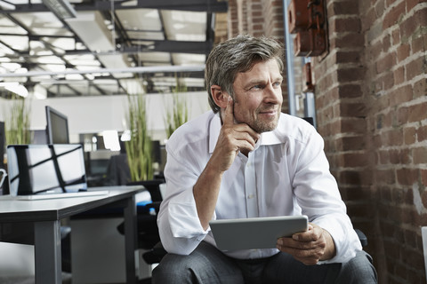 Businessman in office with digital tablet looking to the side stock photo