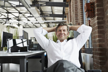 Portrait of smiling businessman in office relaxing - PDF001003