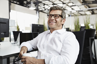 Smiling businessman in office at desk - PDF001007