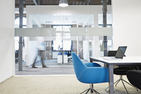 Conference room with blue chair and blurred businessman in the background - PDF001042