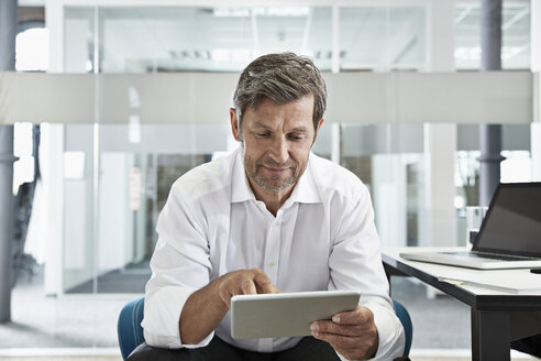 Geschäftsmann im Büro mit Blick auf eine digitale Tafel - PDF001018