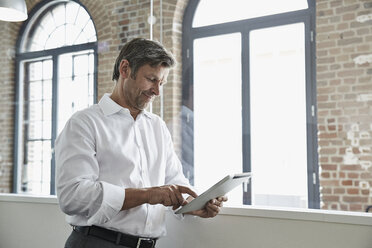 Businessman in office using digital tablet - PDF001040