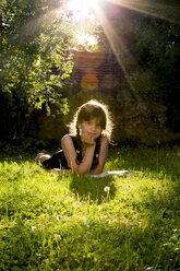 Porträt eines auf einer Wiese liegenden Mädchens mit einem Buch - LVF003495