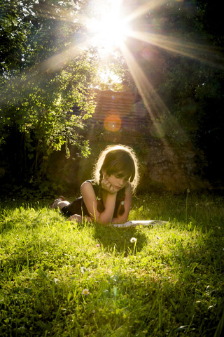 Girl lying on a meadow reading a book stock photo