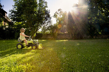 Kleines Mädchen spielt mit Spielzeugtraktor in einem Garten - LVF003503