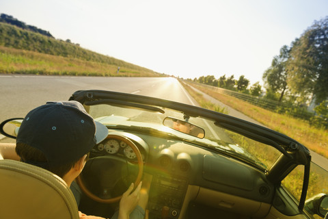 Teenager driving on a country road in a convertible car stock photo