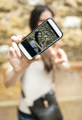 Smartphone mit Foto einer lächelnden Frau, die ein Selfie macht - MGOF000289